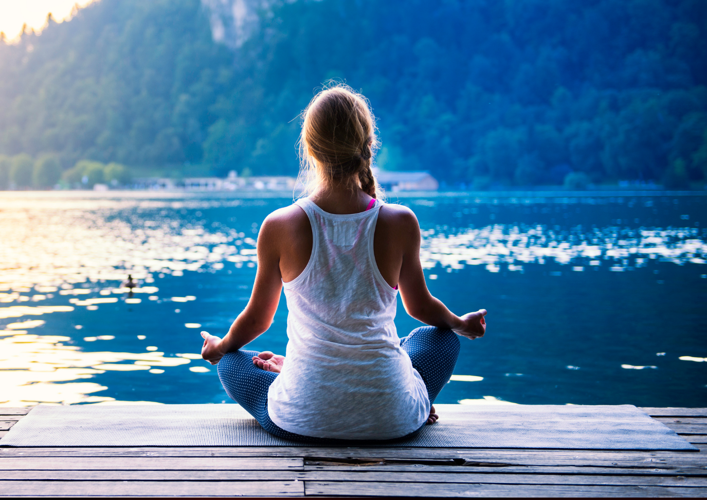woman meditating near lake