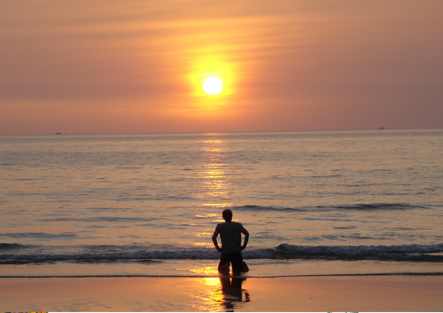 person kneeling along the beach shore